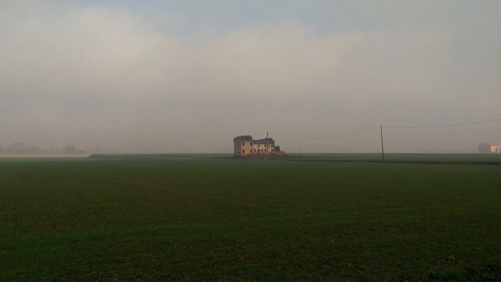 Casa rustica isolata tra i campi, avvolta dalla nebbia della pianura polesana