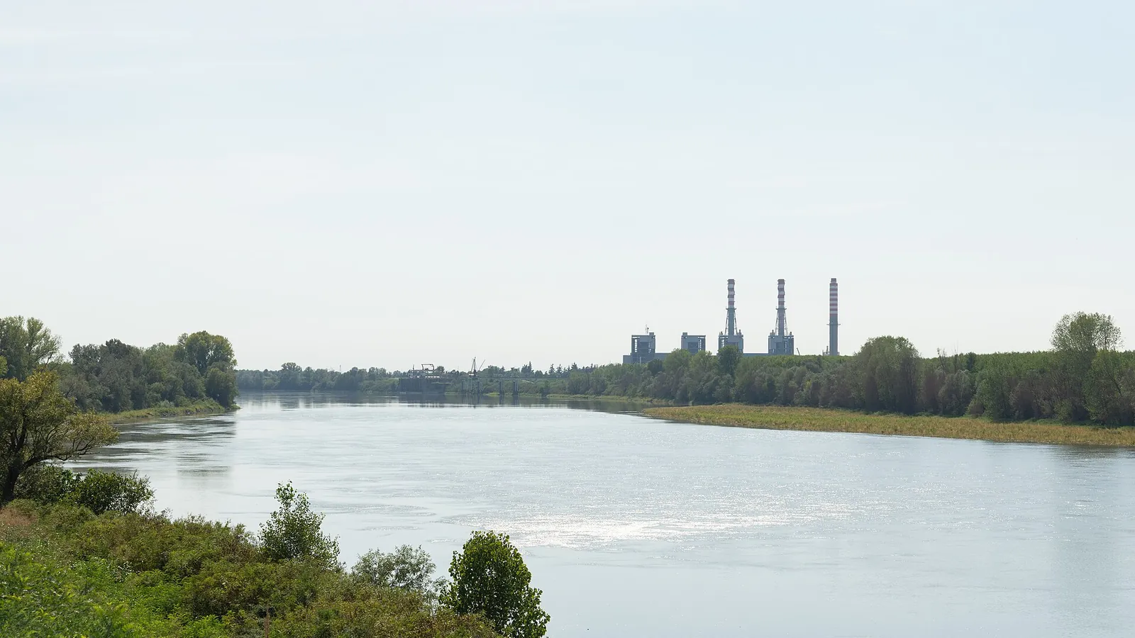 Il fiume Po a Bergantino con le rive verdi e, sullo sfondo, le ciminiere di una centrale