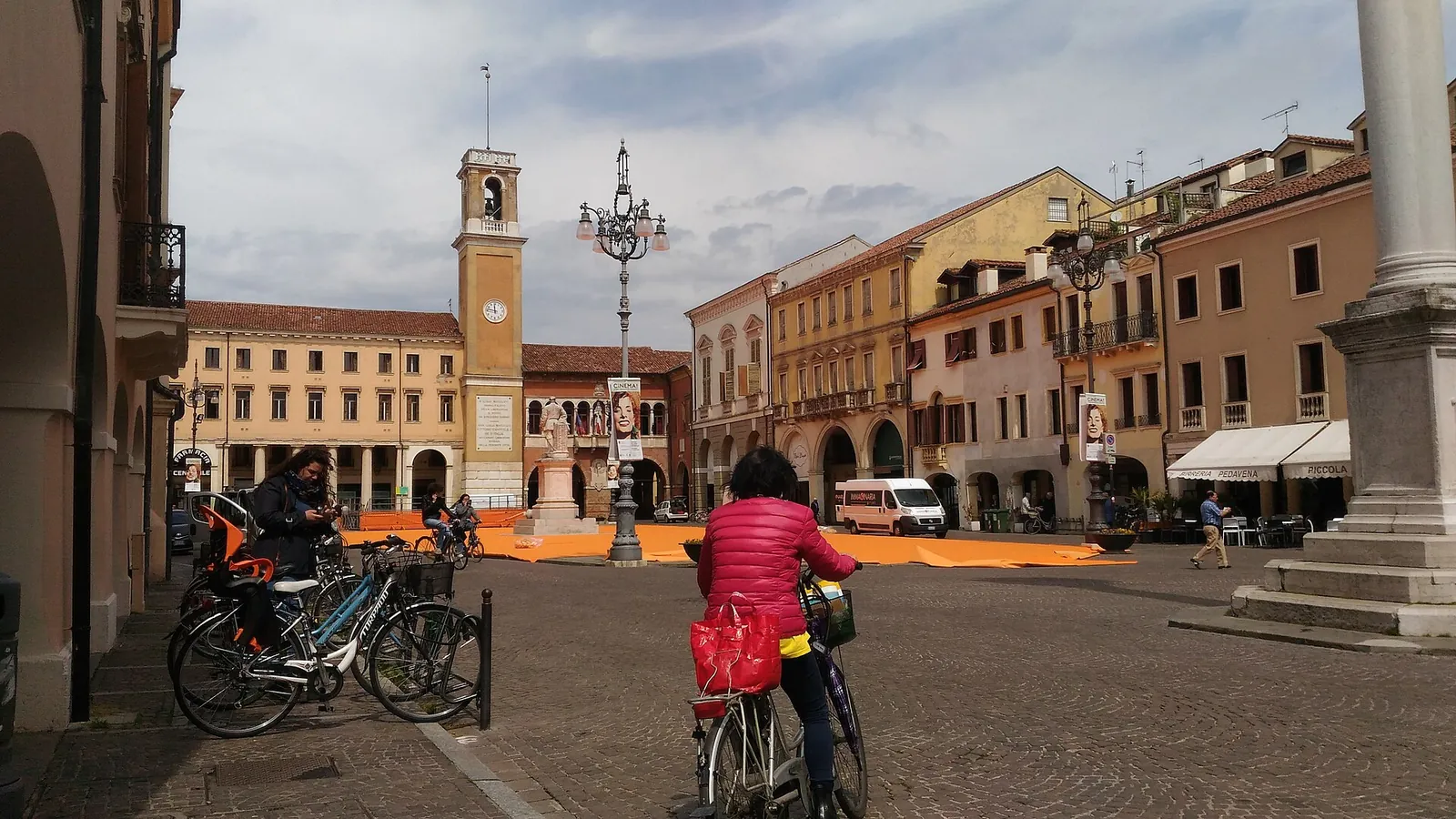 Piazza Vittorio Emanuele II a Rovigo con una ciclista e la torre dell'orologio sullo sfondo