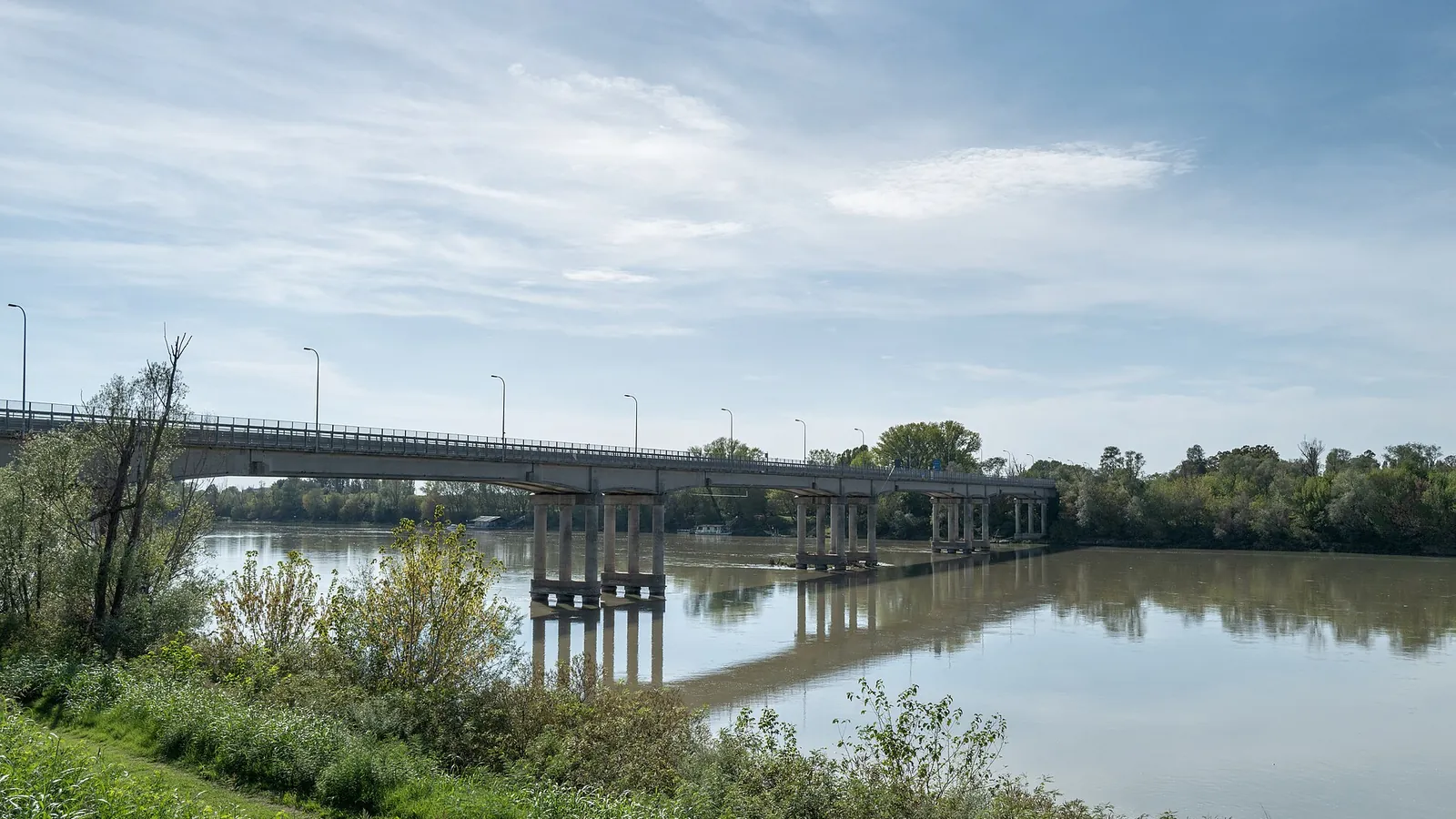 Il ponte sul Po a Ficarolo visto dalla riva, con le nuvole sul fiume